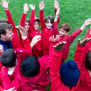 children in red uniforms cheering with their arms in the air