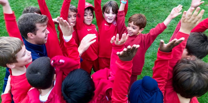 children in red uniforms cheering with their arms in the air